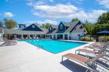 A large swimming pool with sun loungers and a building in the background.