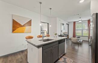 A modern kitchen with a large island and a painting on the wall.