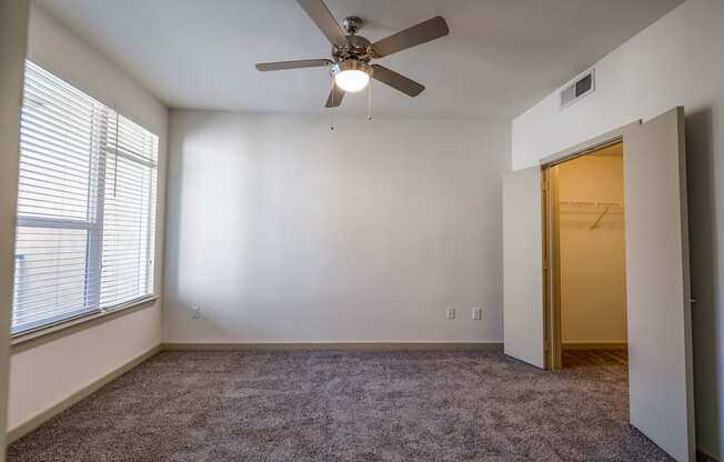 an empty room with a ceiling fan and a door to a closet