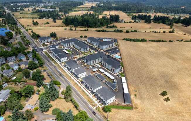 A large building complex is surrounded by a road and a field.