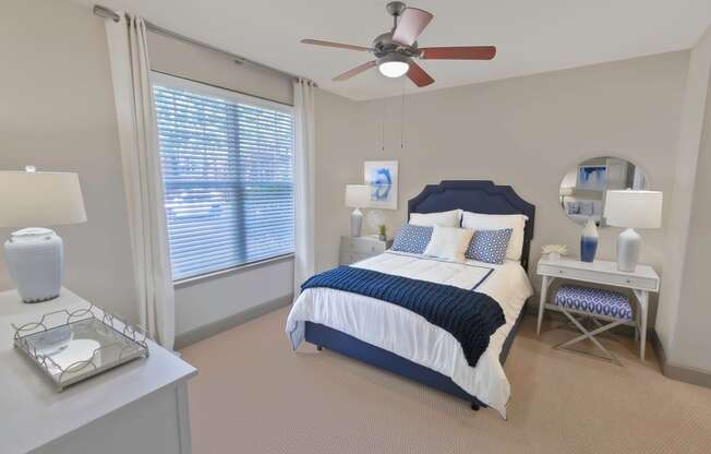 a bedroom with a large window and a ceiling fan