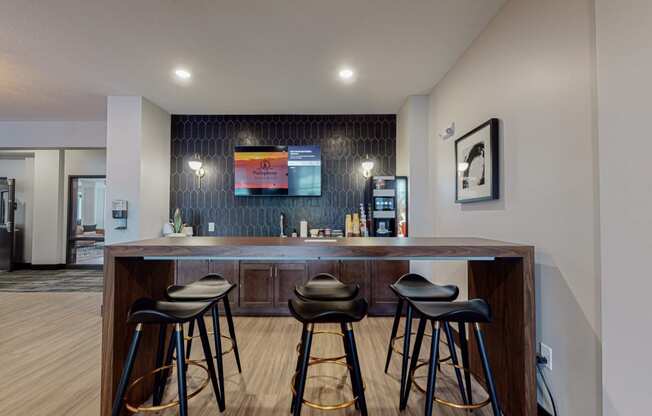 a bar in a hotel room with stools and a tv on the wall