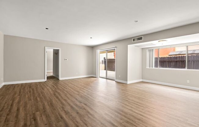 an empty living room with a large window and hardwood floors