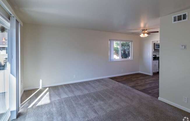 an empty living room with a ceiling fan and a window