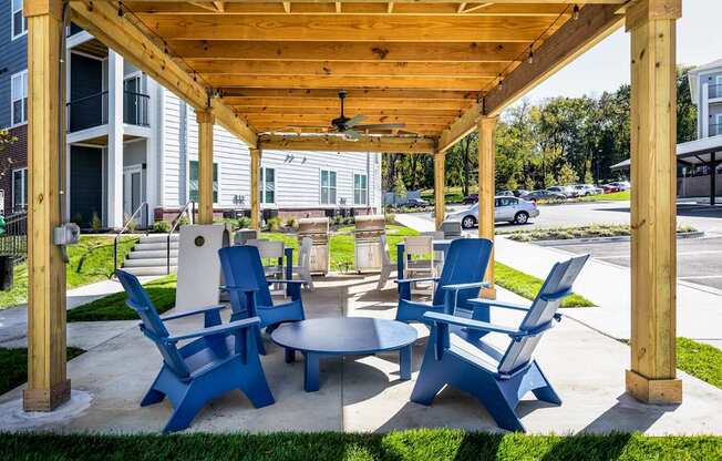 A wooden pergola with blue chairs and a table in the foreground.