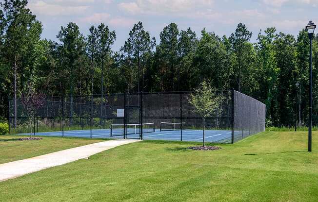 a tennis court in a park with a fence and a scoreboard