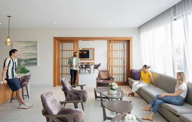 A man in a striped shirt is standing in a living room with two women sitting on a couch. at Palma, Florida