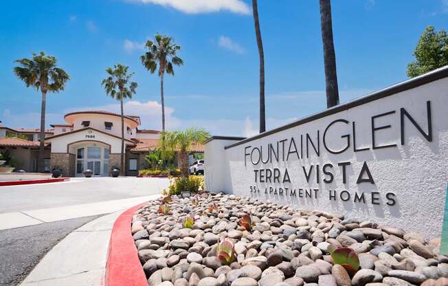 A sign for Fountain Glen Terra Vista apartments is in front of a building with a red curb.