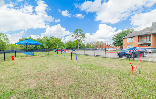 A playground with a blue umbrella and red swing set.