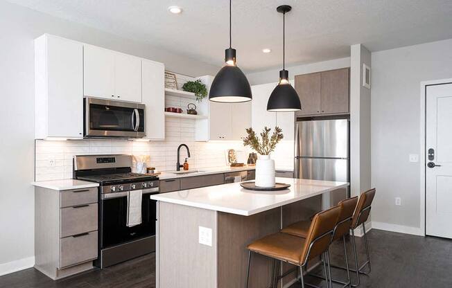 A modern kitchen with a white countertop and brown chairs.