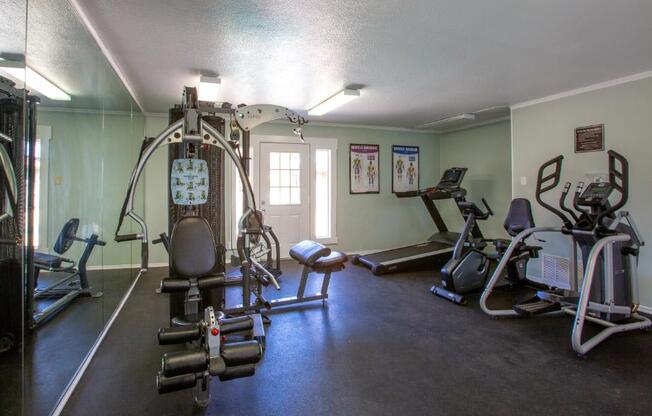 A gym with a variety of equipment including a treadmill, weights, and a bench press.