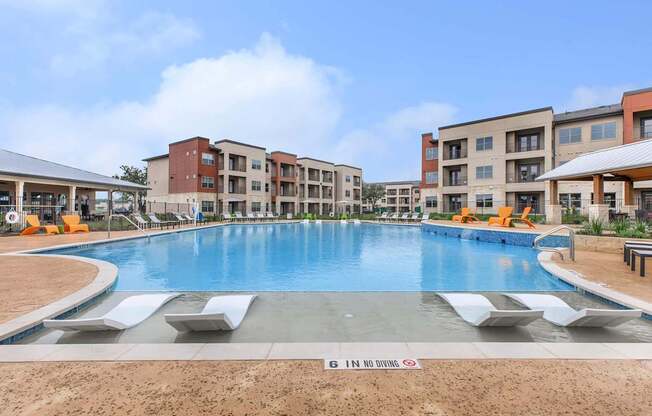 A large swimming pool in front of apartment buildings with a sign that says