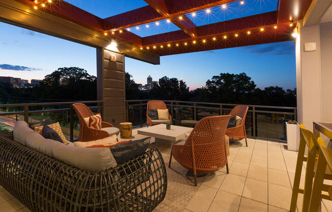 a covered patio with wicker chairs and a table and lights