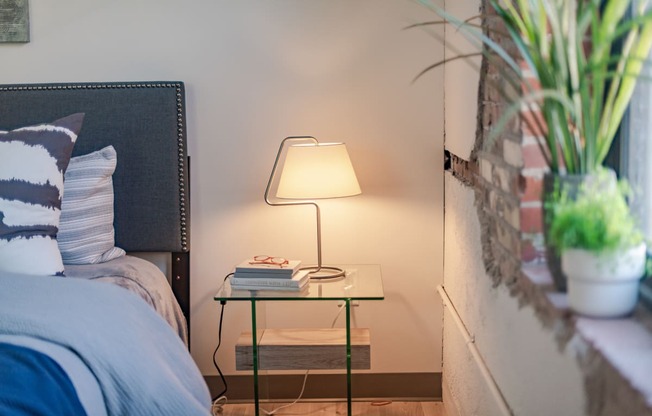 a nightstand with a lamp on it next to a bed at The 22 Apartments, St. Louis Missouri