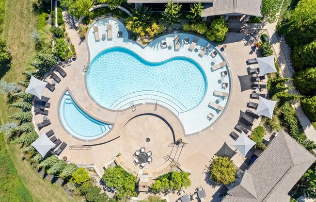 an aerial view of a swimming pool with lounge chairs and trees