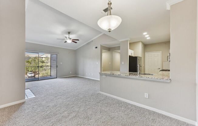 A spacious living room with a ceiling fan and sliding glass doors.