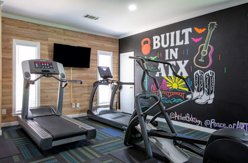 A gym with treadmills and a chalkboard wall that says "Built in Nate".