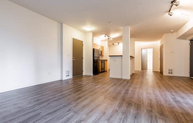 A spacious room with wooden floors and white walls.