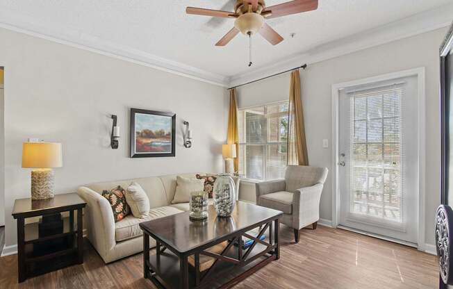 A living room with a white couch, a coffee table, and a ceiling fan.