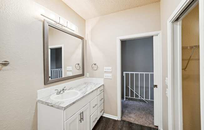 a bathroom with a sink and mirror and a doorway to a closet
