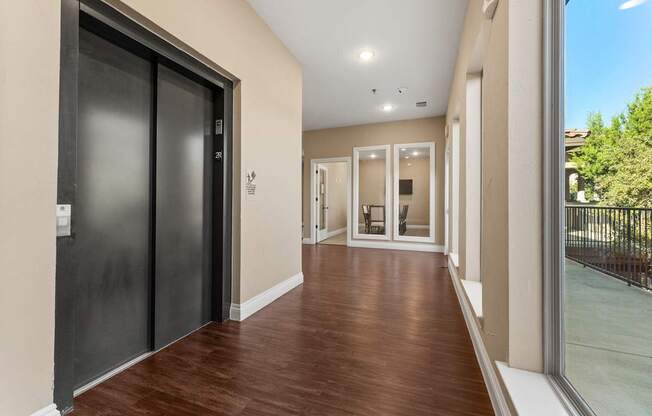 A hallway with a black door on the left and a glass door on the right. at Bridge at Heritage Woods, Austin, TX