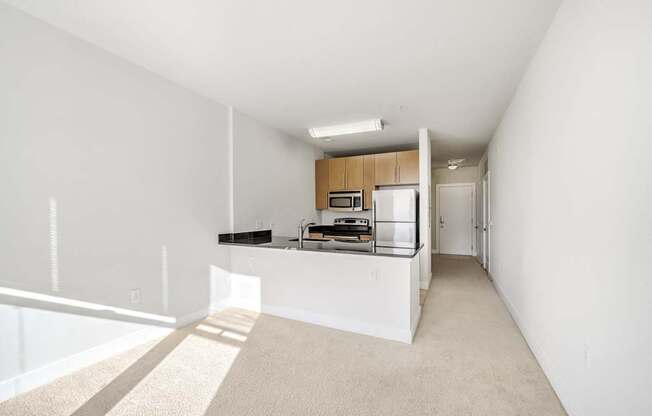 A white room with a kitchenette and a carpeted floor.