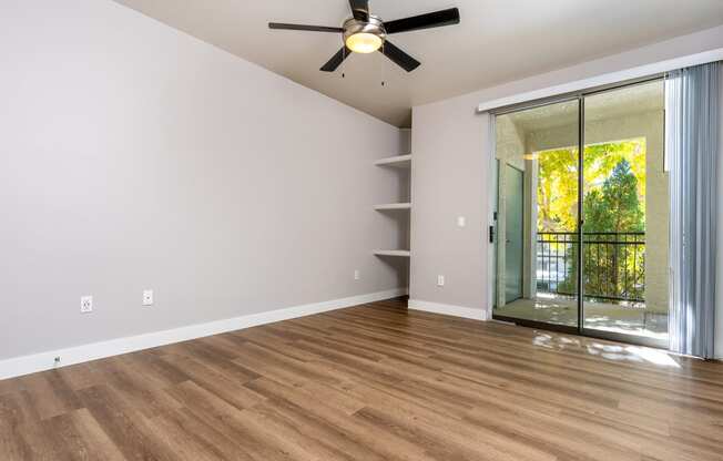 an empty living room with a ceiling fan and a sliding glass door