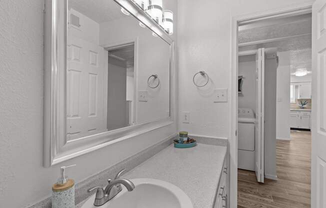 A bathroom with a white sink and a large mirror.
