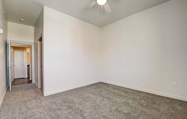 A room with a carpeted floor and a ceiling fan.