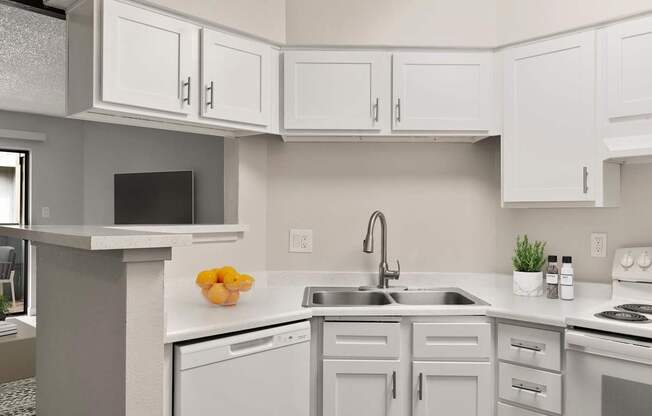 A kitchen with white cabinets and a grey countertop.