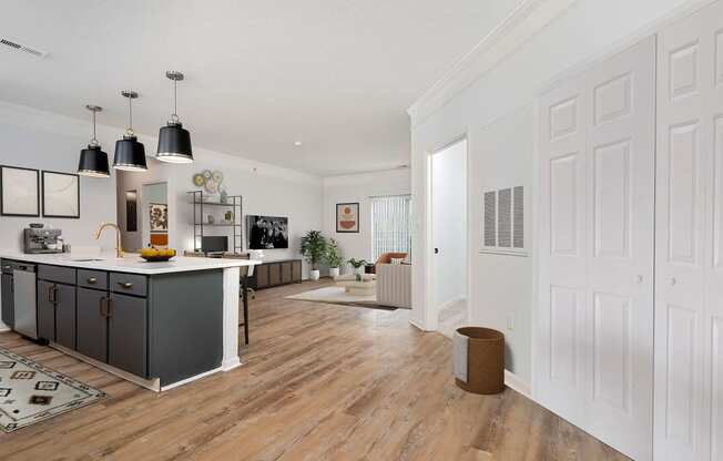 a kitchen and living room with white walls and wooden floors