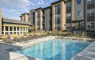 a swimming pool with chaise lounge chairs and a building in the background