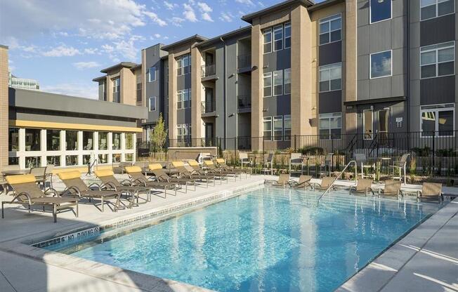 a swimming pool with chaise lounge chairs and a building in the background
