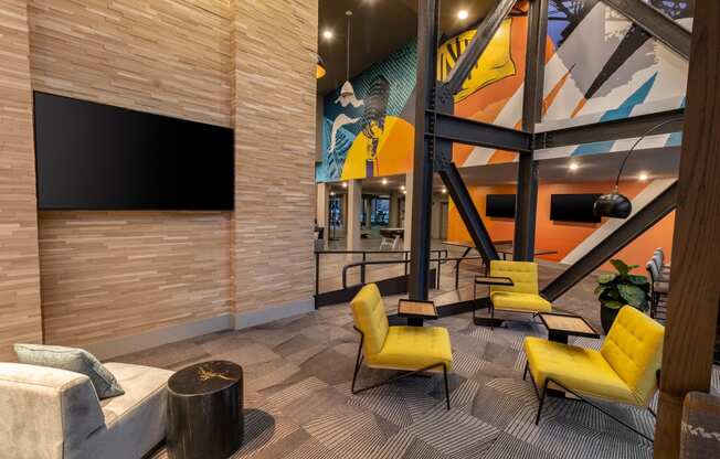 a lobby with yellow chairs and a television