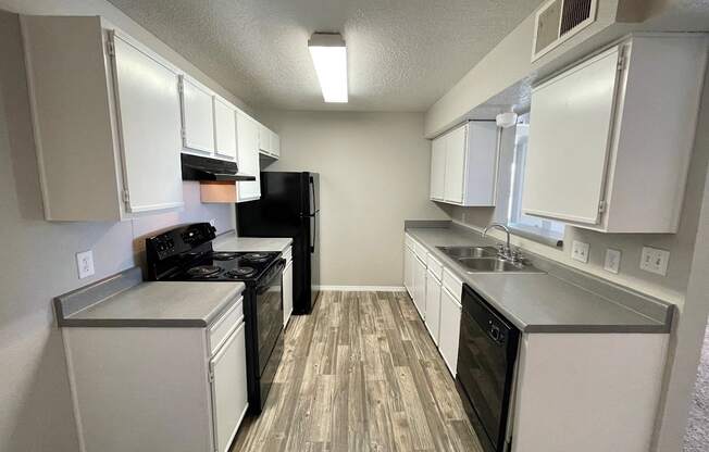 A kitchen with white cabinets and a black refrigerator.