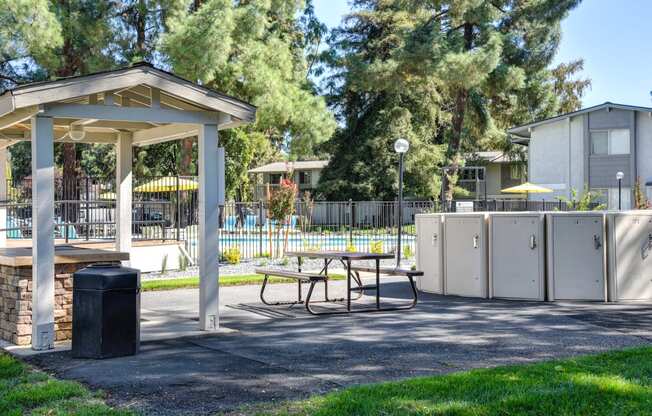 Community BBQ area with a picnic table and a trash can at Renaissance Park Apartments, Davis ,36305