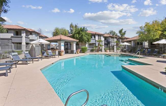 A swimming pool surrounded by sun loungers and umbrellas.