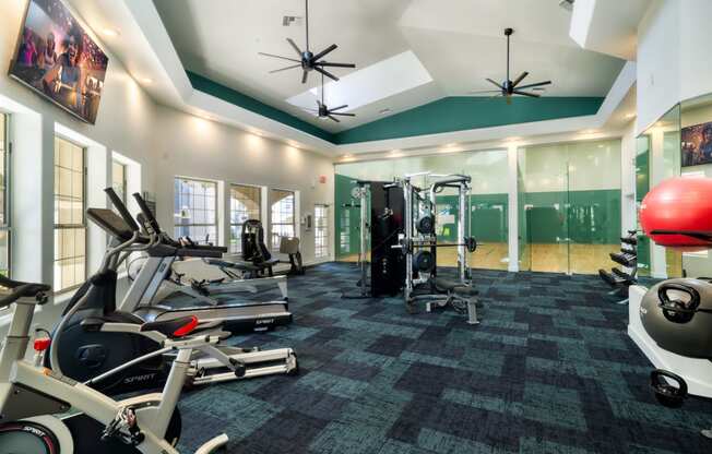 a gym with treadmills and other exercise equipment in a building with green walls