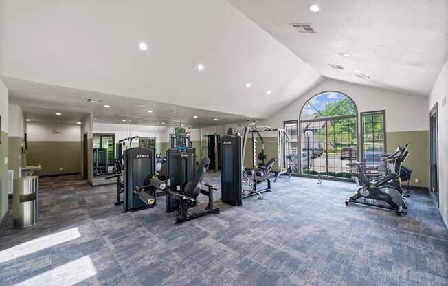A spacious gym with a variety of equipment and a large window.