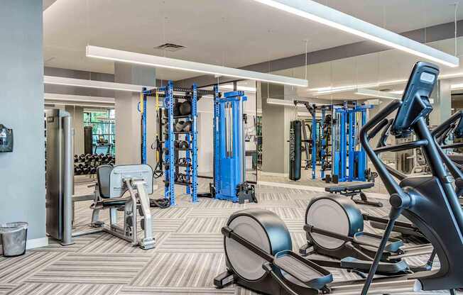 A gym with a variety of equipment including treadmills, weights, and exercise machines.