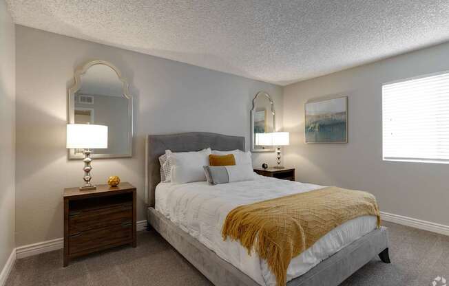 A bedroom with a bed, nightstands, and a mirror.