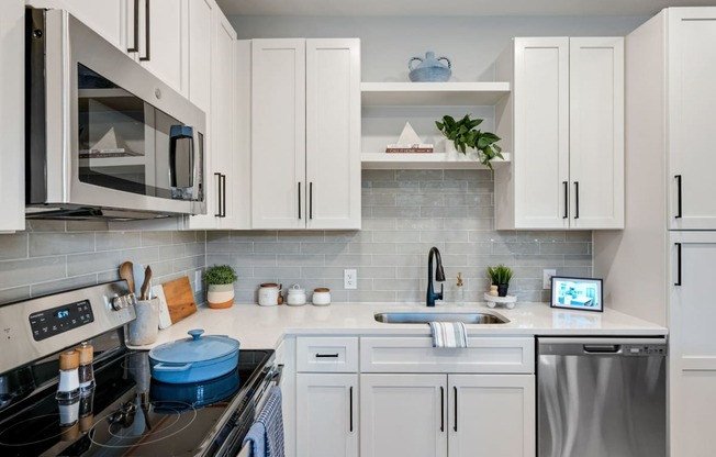a kitchen with white cabinets and appliances and a sink at Preston Ridge, Cary