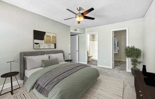 A bedroom with a bed, a ceiling fan, and a painting on the wall.
