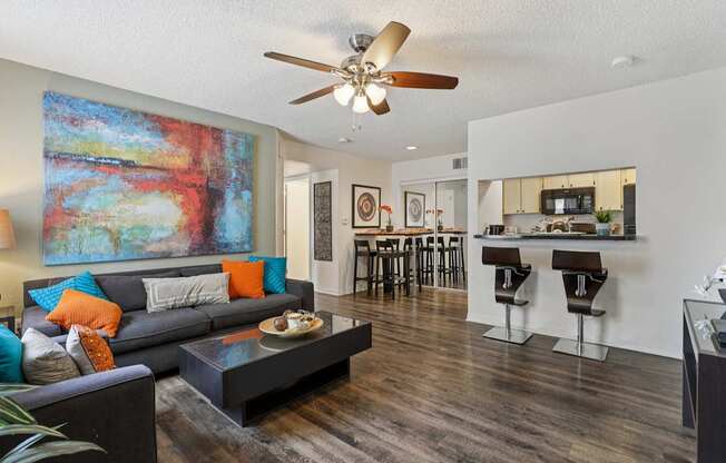 A living room with a grey couch and a painting on the wall.