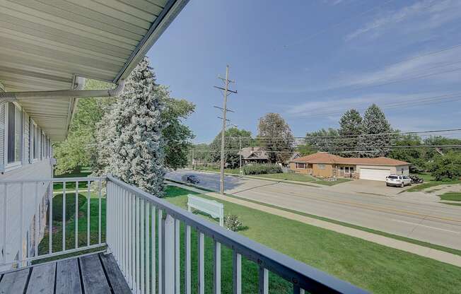 the view from the deck of a house overlooking a street and trees