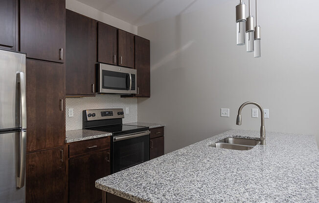 a kitchen with granite countertops and dark wood cabinets