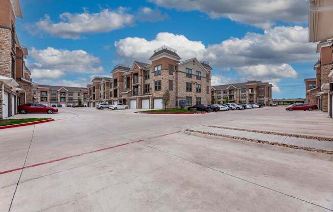 A parking lot in front of a large apartment complex.