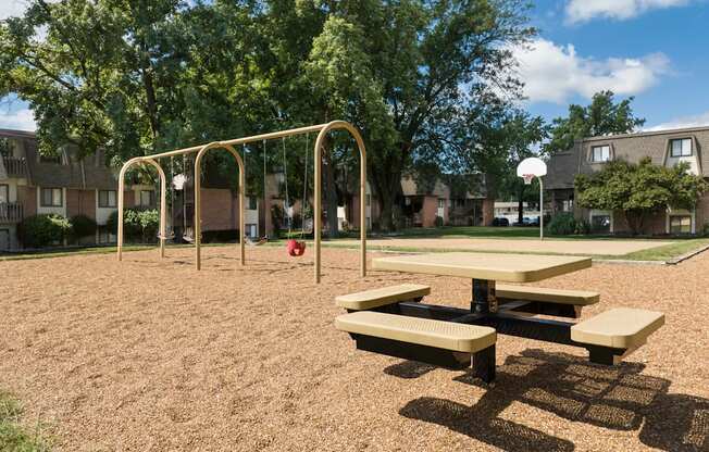 A playground with a swing set and picnic table.