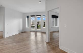 a living room with white walls and a door to a balcony