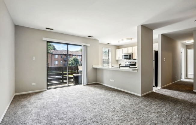 an empty living room with a balcony and a kitchen